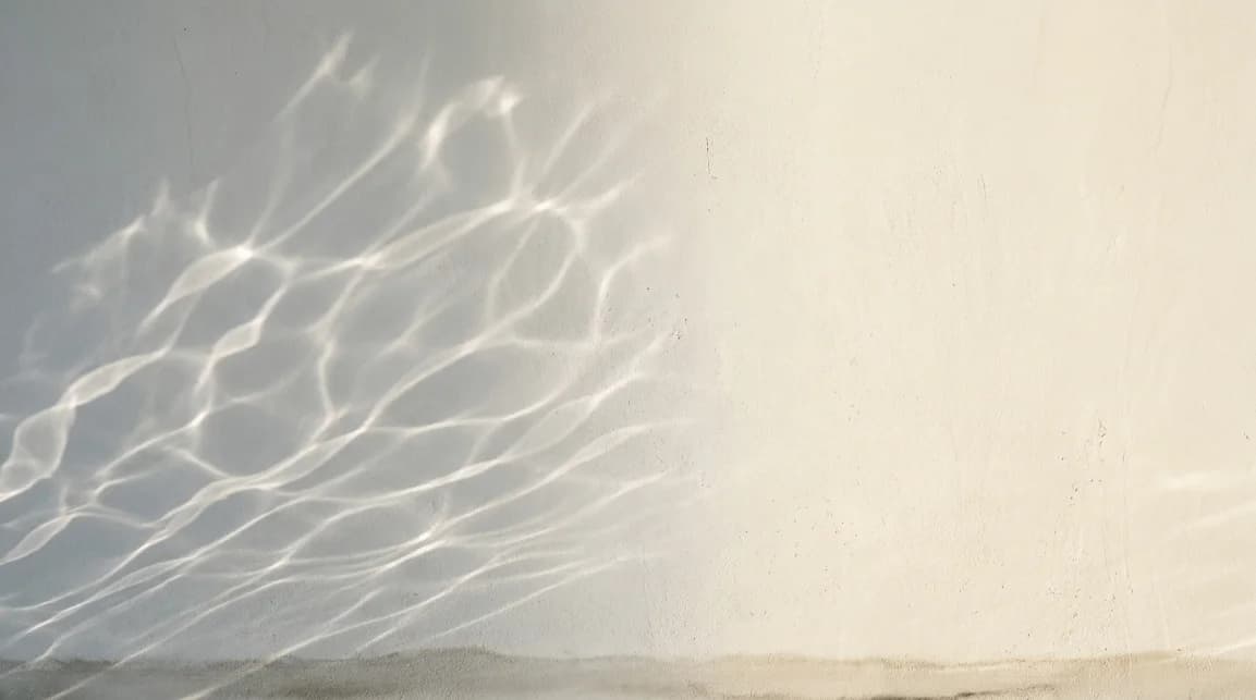Soft caustic light patterns rippling across a plaster wall