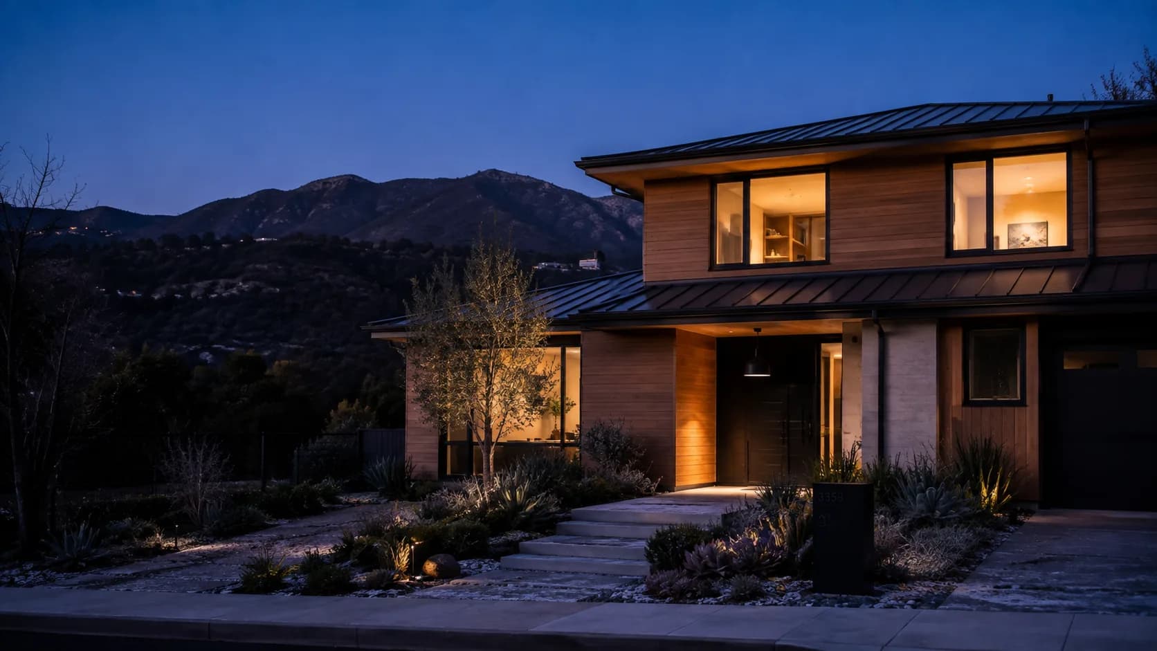 Modern Altadena hillside home intact at blue hour after a wildfire event
